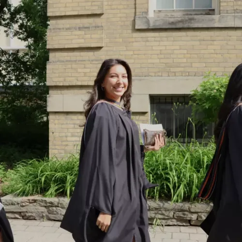 Three graduates wearing gowns and walking 