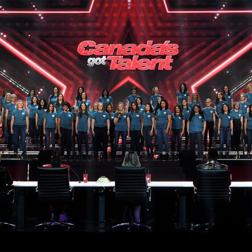 More than 50 women in identical t-shirts stand on a stage under a sign that reads, Canada's Got Talent.
