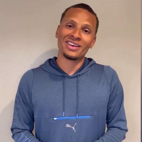 Andre De Grasse smiling and talking on a video call.