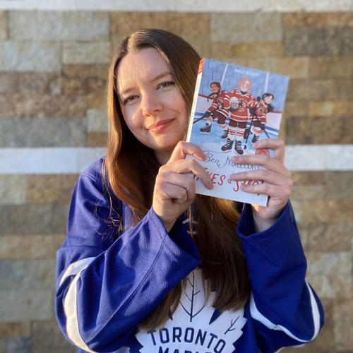 Emily wearing a Toronto Maple Leafs jersey and holding her book