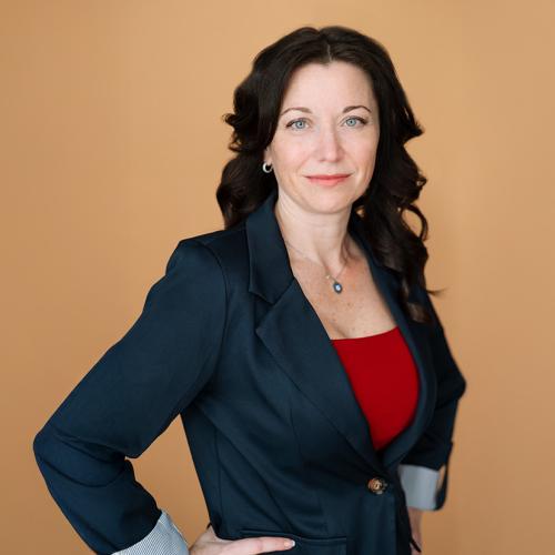 A person in a business suit posing in front of an orange background