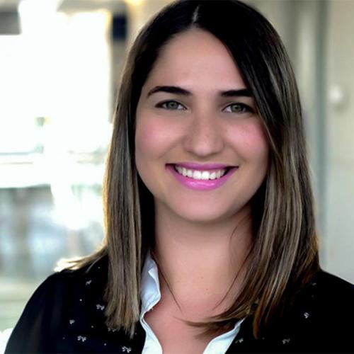 Giovanna Schver smiles while standing in a hallway indoors.