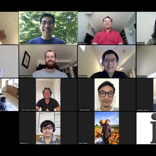 The faces of 14 smiling researchers are seen on a computer screen as they have a video call.