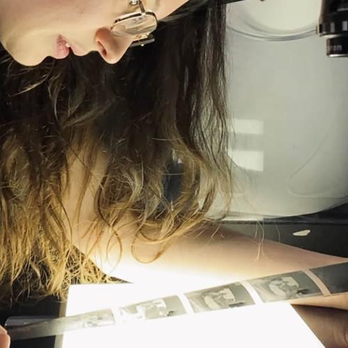 A woman looking at film negatives above a light