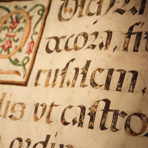 A page of a hand-written medieval manuscript shows ink writing, slightly faded, in old-fashioned letter shapes.