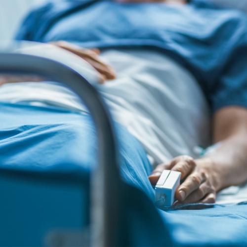 A man lies in a hospital bed with his finger in a monitoring device.