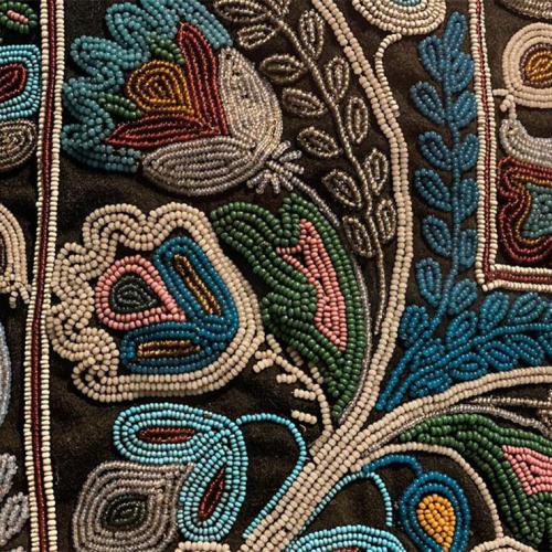 A close-up of miniature beads sewn into an elaborate patterm of leaves and flowers.
