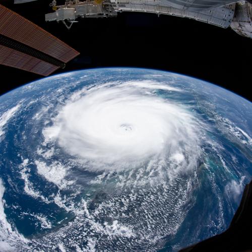 The swirl of Hurricane Dorian covers a large curved segment of the Earth below a metal wing of the International Space Station.