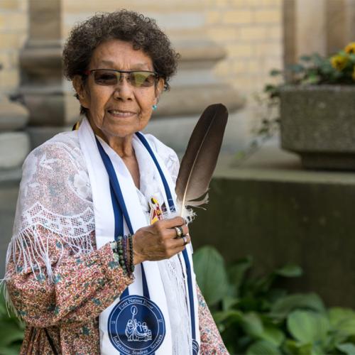 Indigenous elder Jacqueline Lavallee standing outdoors holding a ceremonial eagle feather