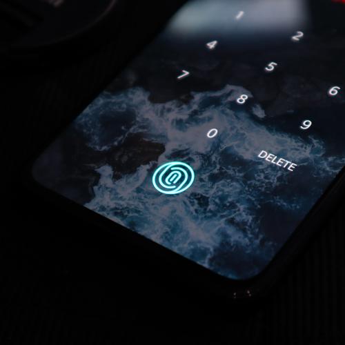 A smartphone screen displayes a fingerprint icon below a numeric keyboard.
