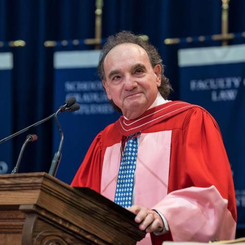Michael Moldaver, wearing academic robes, smiles from the podium at Convocation Hall.