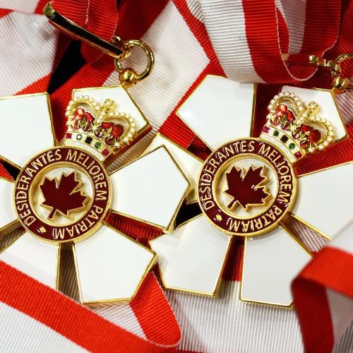 The Order of Canada medal is shaped like a six-petalled flower with a maple logo in the centre and a crown on the top petal.