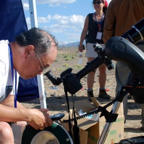 Ralph Choi outside, looking down through a telescope
