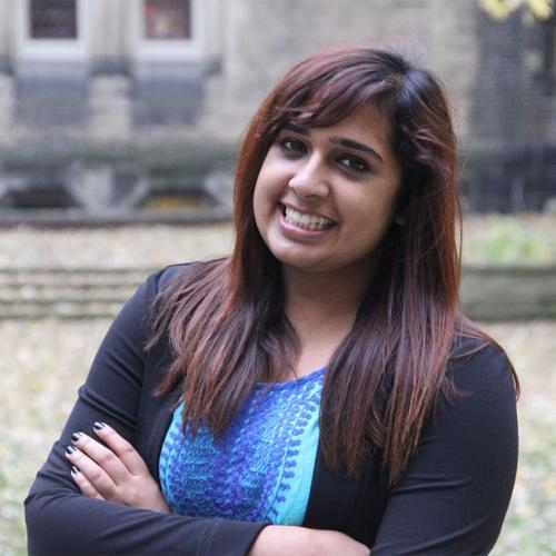 Sarah Qidwai smiles as she stands in a courtyard outdoors.