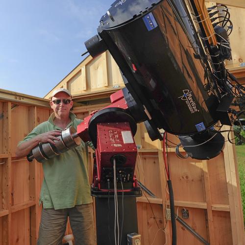 Stuart Heggie stands outside with his telescope.
