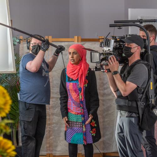 Zarqa Nawaz surrounded by a camera crew