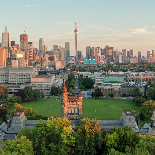 An aerial view of U of T's Front Campus with downtown Toronto behind it, and sunset light washing over the buildings.