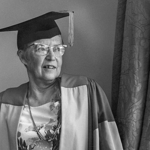 Elsie McGill smiles and looks out a window while wearing academic robes--and cat-eye glasses--in 1973.