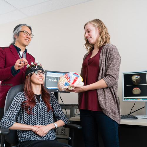 Professor Tom Chau, a University of Toronto pediatric rehabilitation engineer, works with two graduate students to develop a brain-computer interface for children (photo by Neil Ta)