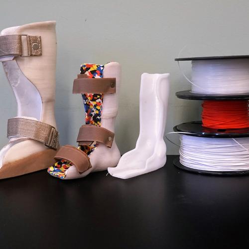 Three custom walking casts stand next to colourful reels of 3D printer filament (photo courtesy of Nia Technologies) 
