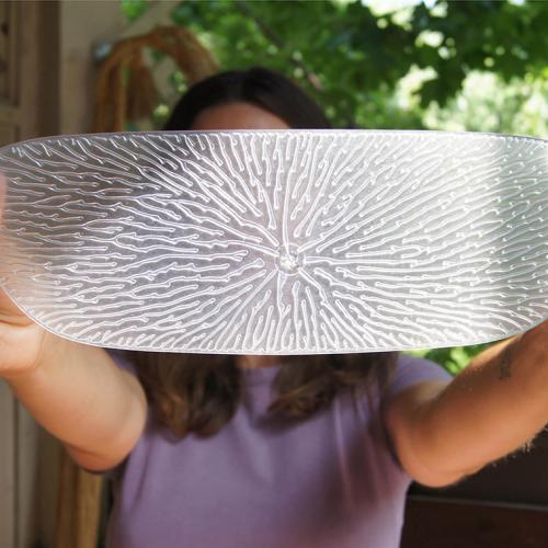 A woman holds up Undu, a thin silicone oblong covered with tiny branching veins.