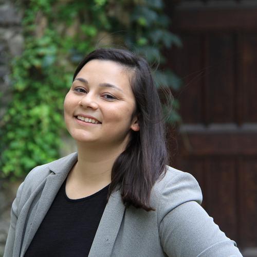 Emmalin Buajitti smiles, standing with hands on hips in front of an ivy-covered building.