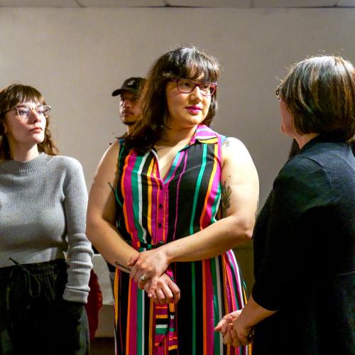 Animikiik’otcii Maakaai smiles as she chats with a woman in a crowd at an art gallery.