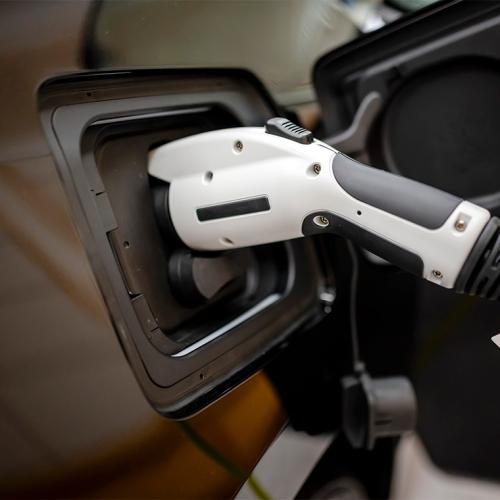 A charging cable is plugged into an electric car. (photo by Vitpho via Getty Images) 