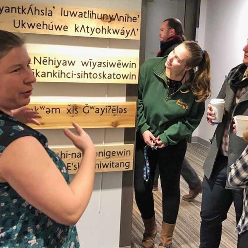 Rochelle Allan, left, acting manager of the Indigenous Initiatives Office, views the language installation -- five boards made from traditional wood and carved with Indigenous languages -- with U of T law students (photo by Lucianna Ciccocioppo) 
