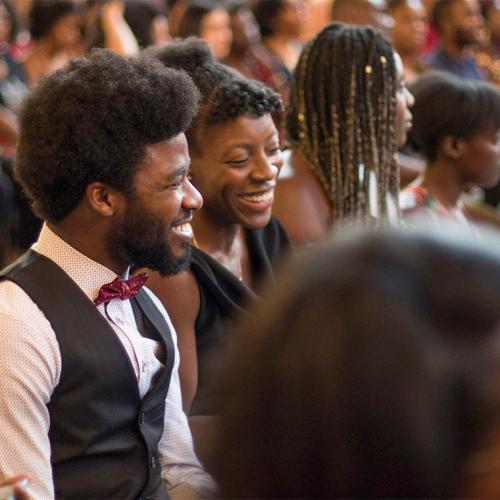 People laugh together as they sit in the audience for U of T's Black Graduation ceremony.
