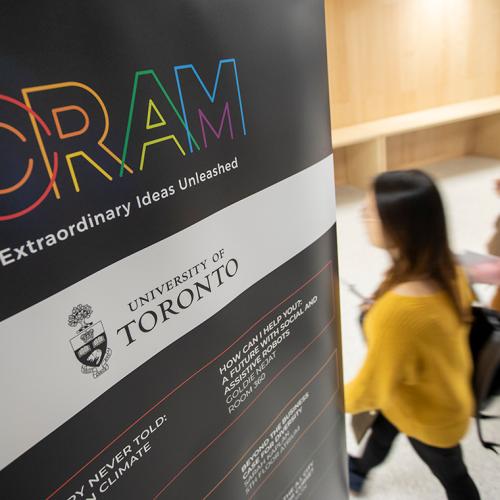 Two people walk into a lecture room near a sign advertising the CRAM festival at U of T (photo by Nick Iwanyshyn) 