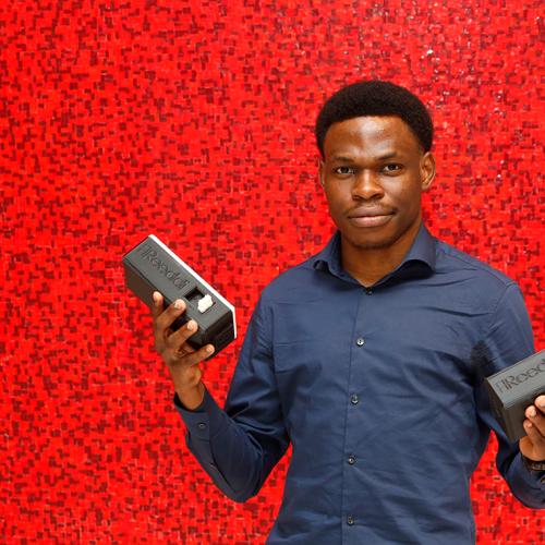 Olugbenga Olubanjo holds up two small rectangular plastic capsules with the Reeddi logo and plug sockets on the end.