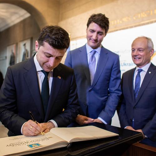 Volodymyr Zelenskyy signs U of T's guest book Prime Justin Trudeau and  Meric Gertler look on.