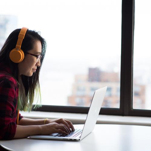 Alum wearing headphones and using laptop