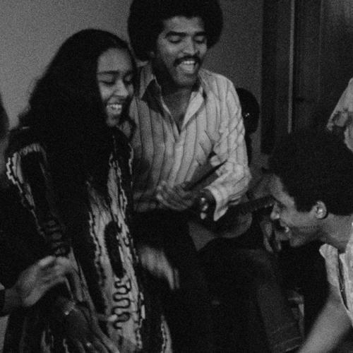 A film still from OYOYO (1980) showing a group of people smiling and clapping.