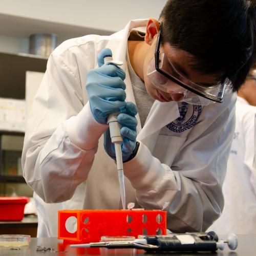 A high school student using a pipette in a science lab