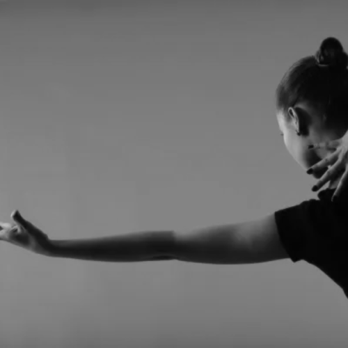 A contemporary dancer striking an artistic pose with their arm extended.
