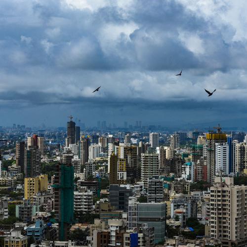 Cityscape of Mumbai, India with high-rise buildings and birds flying in the sky.