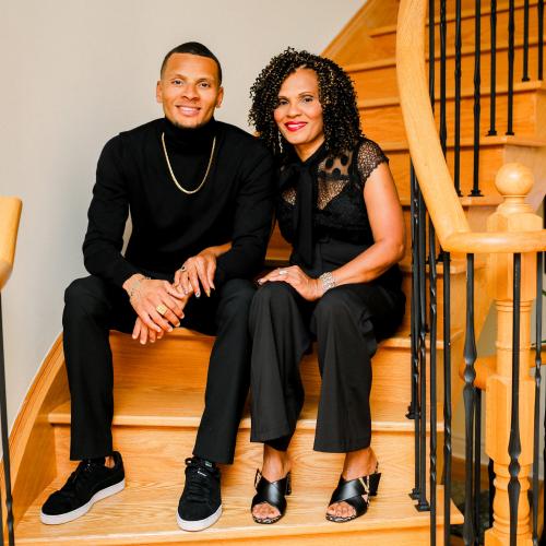 Andre De Grasse, his mother Beverley De Grasse, black male and female, shown smiling and sitting on stairs. 