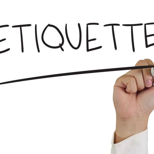 a hand holding a marker with the word "etiquette" on a white board.