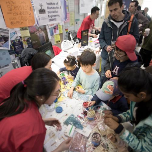 Image shows student volunteers and children doing science experiments.