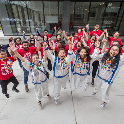 Image shows a group of student volunteers jumping in the air.
