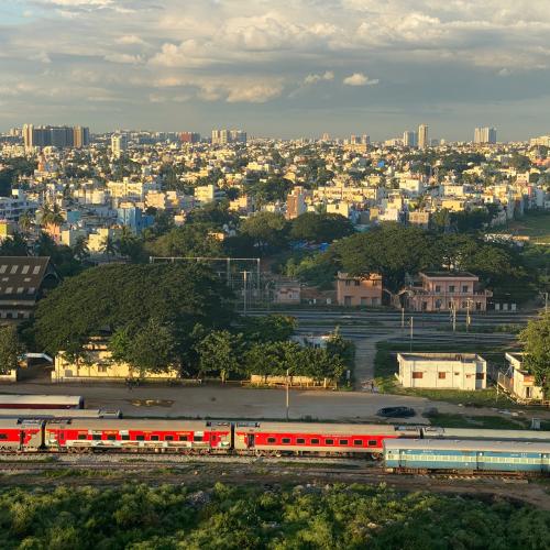 Bengaluru skyline. Trains in front, foliage in middle distance, buildings in far distance.