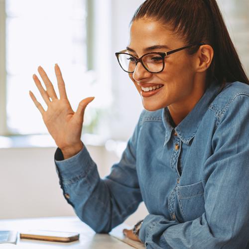 Person waving at computer screen