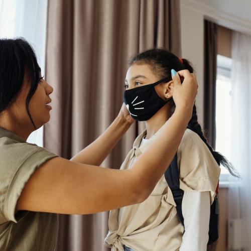 Caregiver helping child with mask