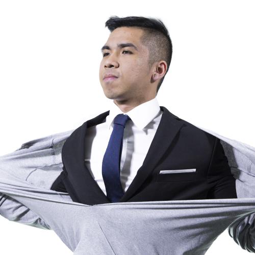 Young man rips open sweater to reveal a suit and tie.