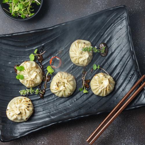 5 Dim Sum dumplings on a black rectangular dish
