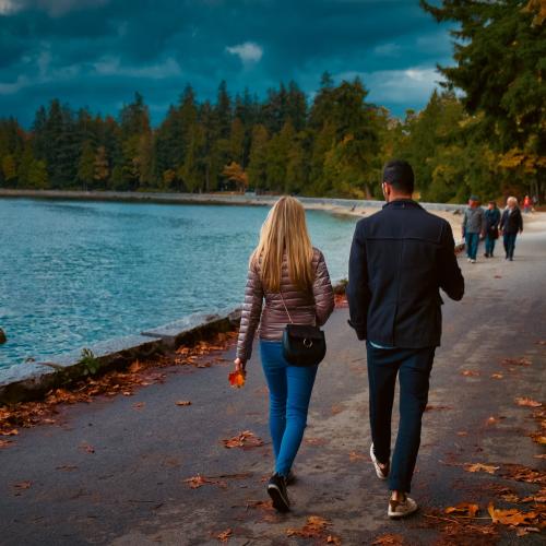 Two people walking along the water with on an autumn day
