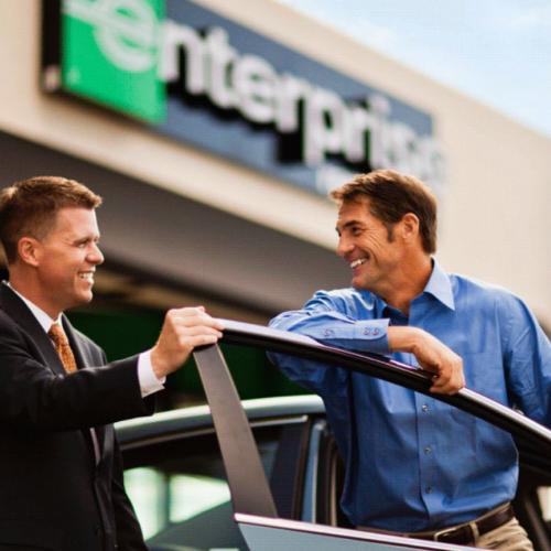 Man smiling as an Enterprise car rental employee shows him his rental car