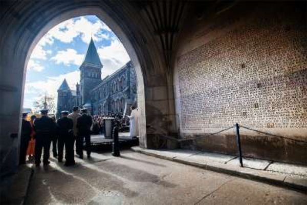 A group of people stand under a stone archway at the Soldiers' Tower with the blue sky shining behind them